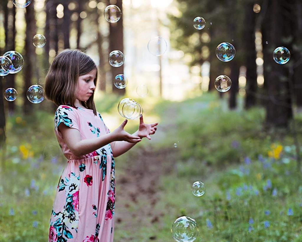 family photography session in Cle Elum little girl in pink dress catching bubbles