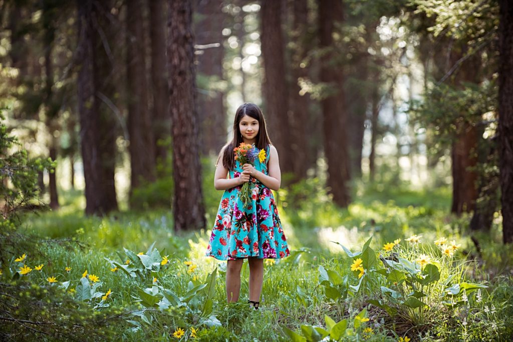 Young brunette holding flowers in the forest in photography session by Mary Maletzke photographer in Cle Elum