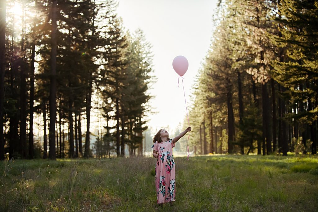 Image of a girl in a pink dress holding a balloon in the forest by Mary Maletzke photographer in Cle Elum