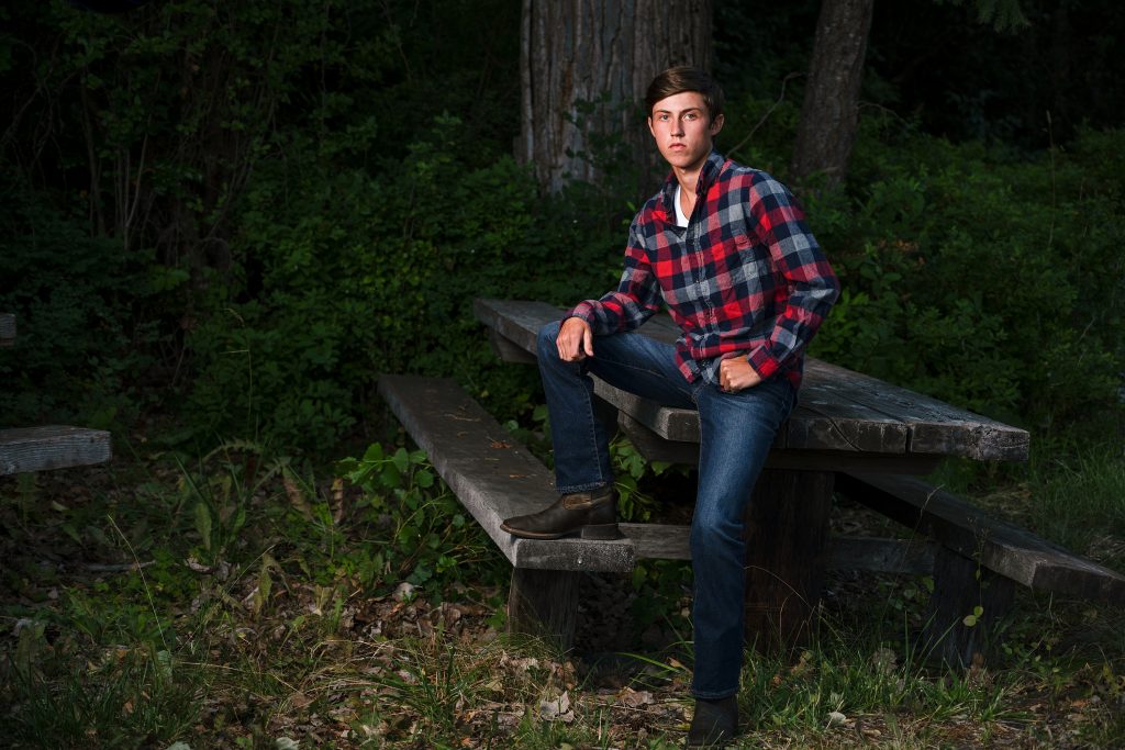 Traditional Senior Portrait of a high school student posing against a table wearing flannel