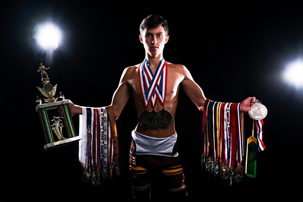  Senior Photos of highschool boy holding multiple wrestling medals and trophys