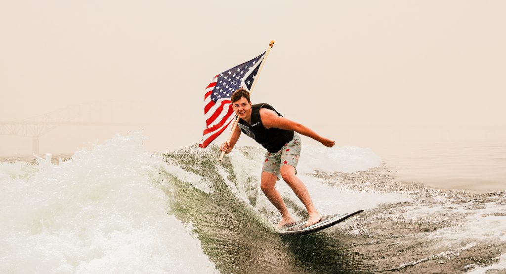 highschool senior photographer young man wakeboarding with american flag