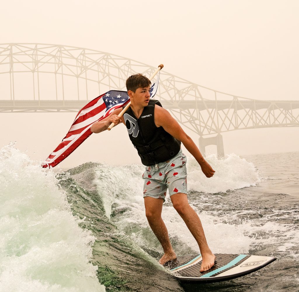 High school student wakeboarding with american flag in ellensburg washington