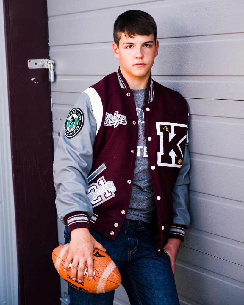 High school Football Player posing with football and letterman jacket ellensburg washington
