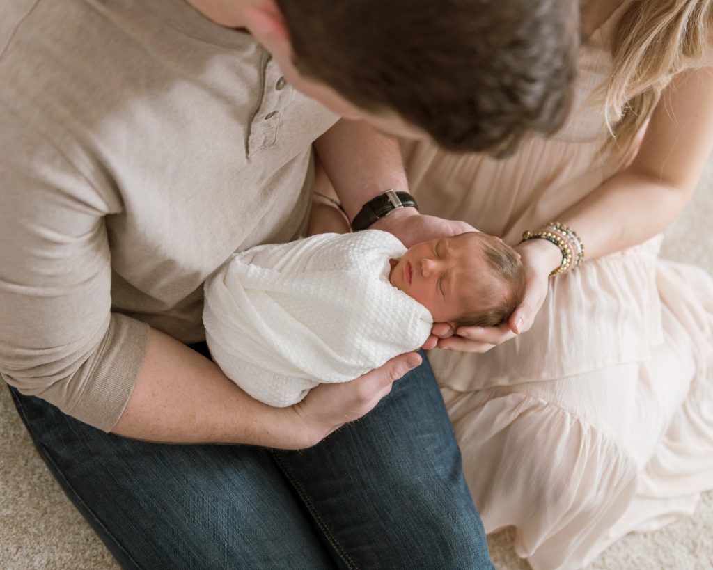 Photo of new dad snuggling baby daughter on his lap in nursery Suncadia Family Photographer