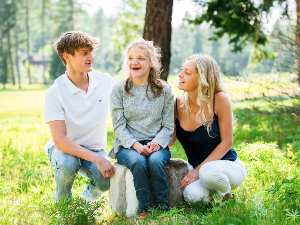 Three teenage children smile at the camera 