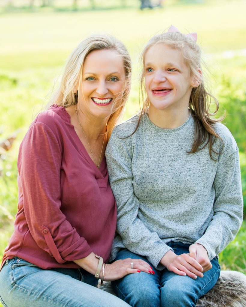 Mom snuggles with her young teen daugther during family portraits