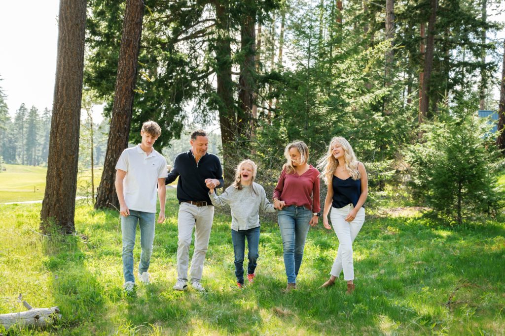 Two parents walk through a wooded field with their three teenage children